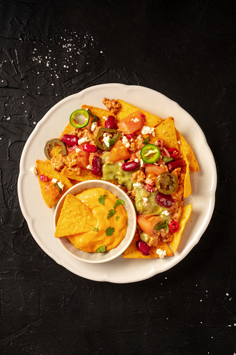 Nachos with beef, guacamole and cheese sauce, top shot on a black background with a place for text