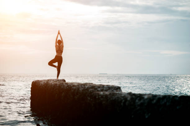istock Asian fitness runner body closeup doing warm-up routine on beach before running, stretching leg muscles with standing single knee to chest stretch. Female athlete preparing legs for cardio workout. 1300938363