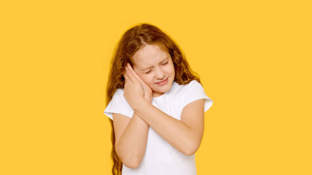 istock Sad little girl with earache on a yellow background. 1300939169
