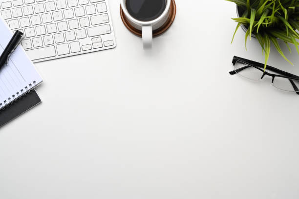 istock Top view of office desk with coffee cp, glasses, keyboard, notebook and copy space. 1300943256