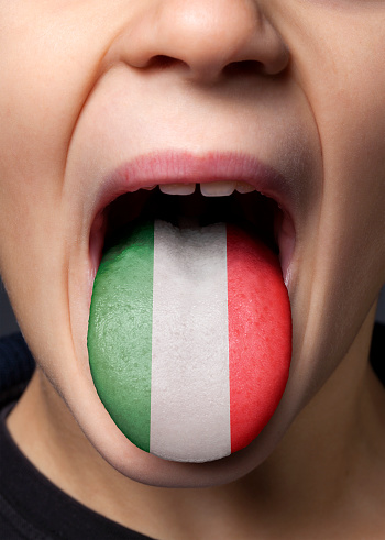 Little boy sticking out his tongue with painted Italian flag.