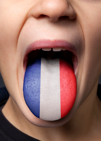Little boy sticking out his tongue with painted French flag.