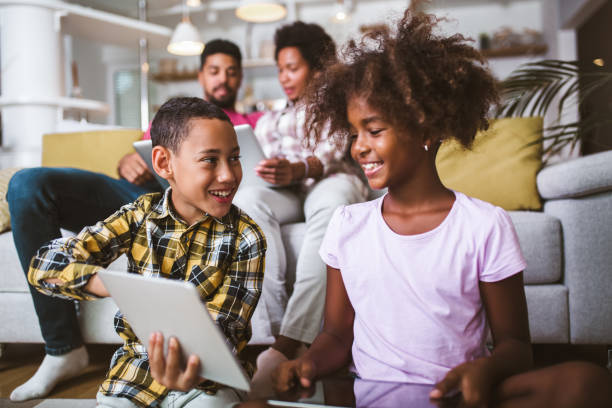 istock African american boy and girl lying on floor and using digital tablet. 1300945774