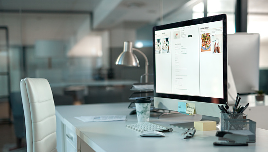 Shot of a dek in a modern office setup with a chair and desktop computer