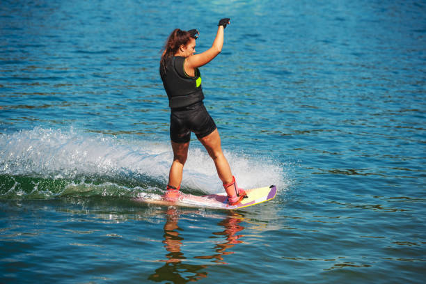 istock Young woman finishing wakeboard ride with a splash 1300947041