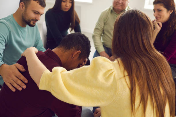 istock Friendly diverse people supporting an upset young man in a group therapy session 1300947132