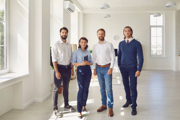 istock smiling business partners or project team standing and looking at camera in modern office 1300948011