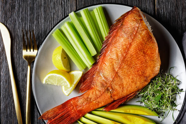istock cold-smoked red snapper served with celery sticks, avocado slices and microgreens on a grey platter on a rustic wooden table, horizontal view from above, flat lay, macro 1300949366