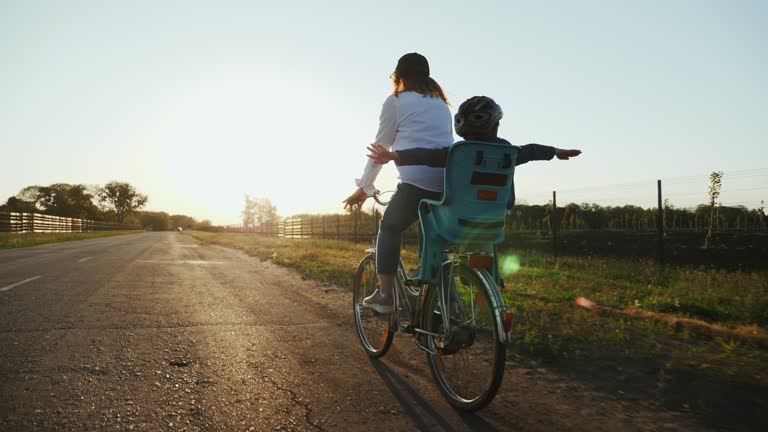 Mom with her little son are riding a bike on the road