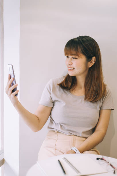 istock Asian woman using mobile phone at coffee shop 1300950560