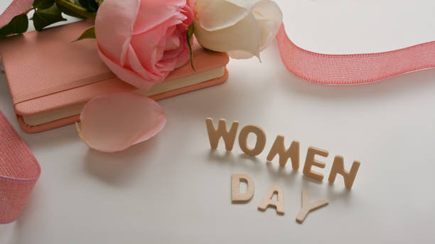 istock Women's Day message with notebook, pink roses and ribbon decorated on white background 1300953002