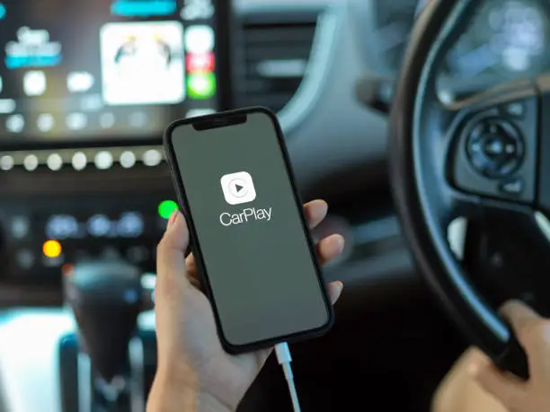 CHIANG MAI, THAILAND - MAY 11, 2020 : female hand holding smartphone with CarPlay application. CarPlay is a application allows you to view content from your iPhone on your car's infotainment screen