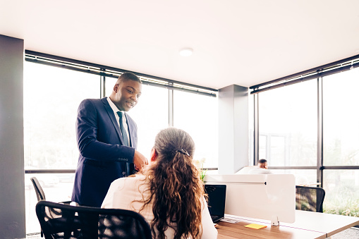 Confident male professional discussing with female colleague. Colleagues planning at desk in office.