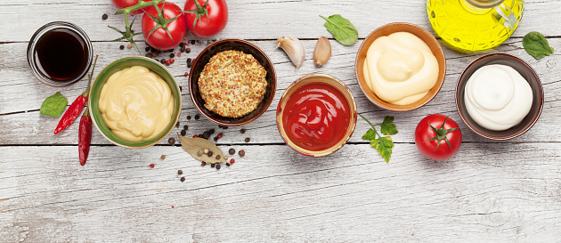 Set of various sauces. Popular sauces in bowls - ketchup, mustard, mayonnaise on white wooden table. Top view flat lay