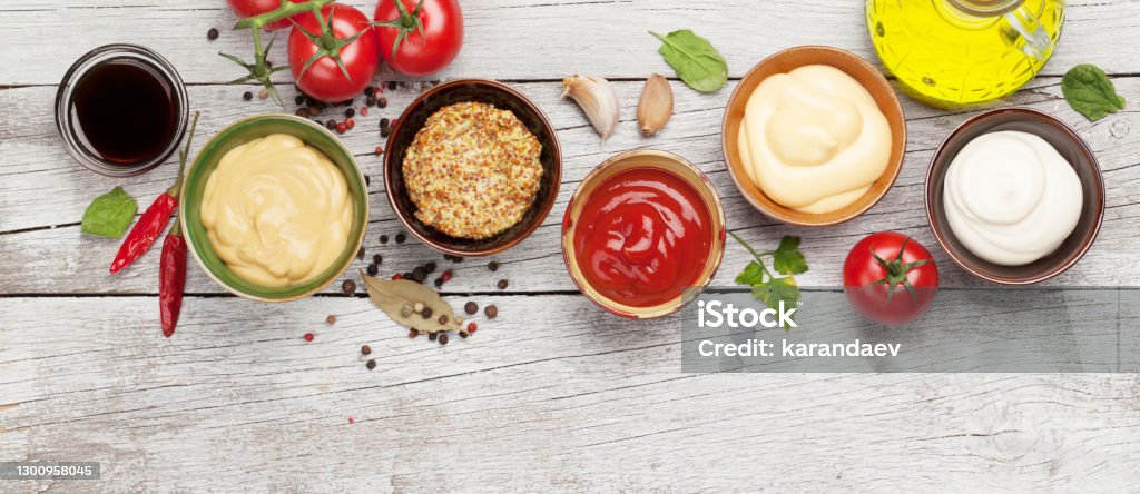 Set of various sauces. Popular sauces in bowls Set of various sauces. Popular sauces in bowls - ketchup, mustard, mayonnaise on white wooden table. Top view flat lay Condiment Stock Photo