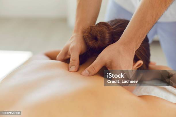 Young Woman Enjoying Relaxing Remedial Body Massage Done By Professional Masseur Stock Photo - Download Image Now