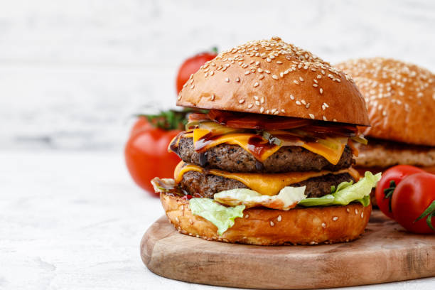 istock Freshly cooked burger on wooden board on light background 1300958370