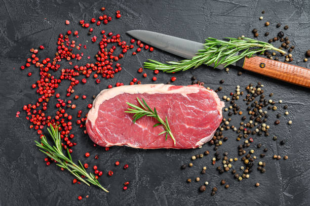 istock Raw striploin steak or strip New York with herbs. Black background. Top view 1300960492