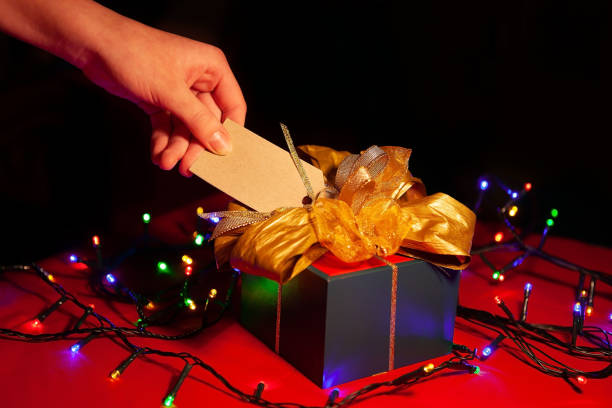 istock A woman's hand holds a label on a gift box with a gold bow. 1300960599