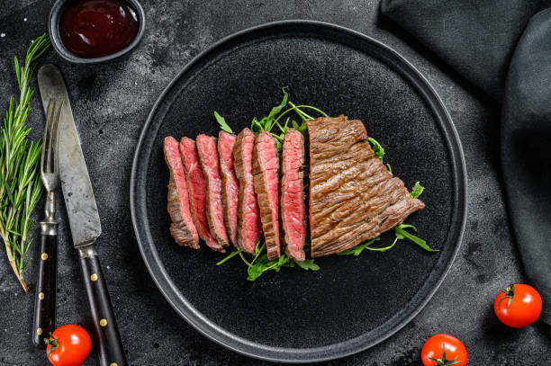 istock Grilled and cut flank steak. Marble beef meat. Black background. Top view 1300961717