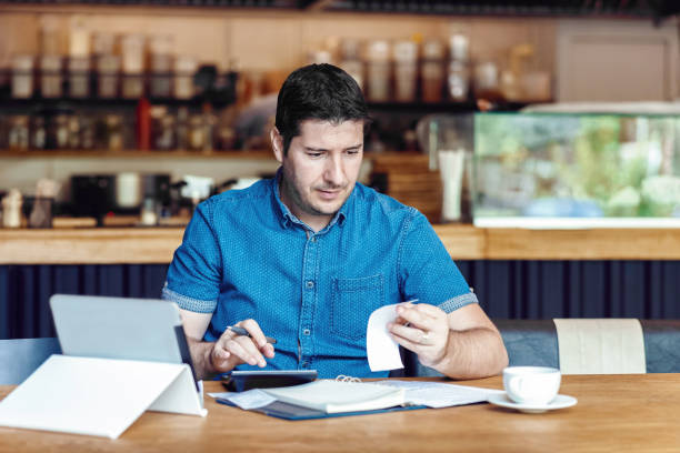 maduro nuevo propietario de pequeña empresa calculando gastos e impuestos en facturas de restaurantes en línea - restaurant wireless technology office worker business fotografías e imágenes de stock