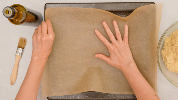 istock Woman's hands placing parchment paper onto a baking pan, close up baking process, flat lay 1300961969