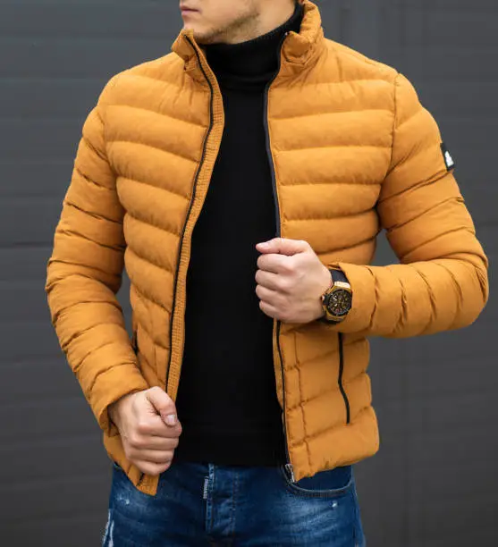 Young handsome guy in a warm knitted clothes against a background of black wall