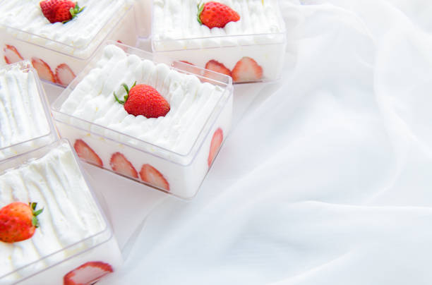 Strawberry mousse pastries topped with whipped cream and fresh strawberries on a restaurant table. Close-up. Selective focus.