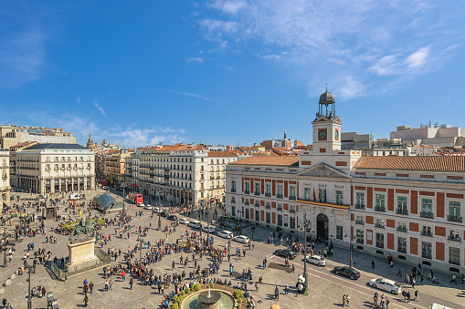 Exterior view of Almudena Cathedral on a sunny afternoon, Madrid, Spain. Many tourists at the Plaza de Armeria can be seen.
