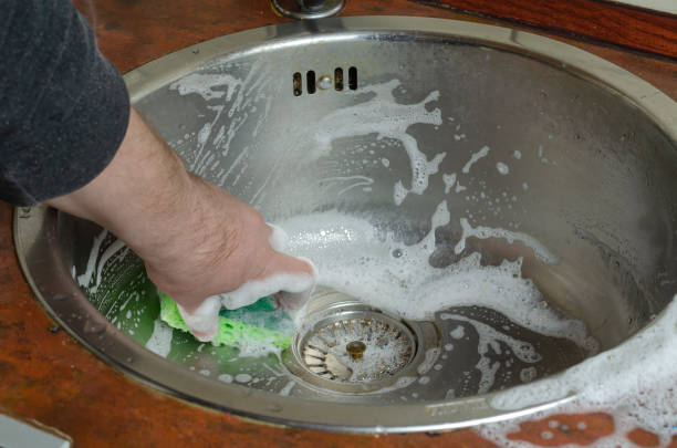 istock A man's hand washes the kitchen sink with a dish sponge. 1300963914