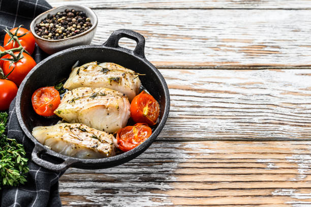 istock Fried cod fish fillet with spice in a cast iron pan.  White background. Top view. Copy space 1300964629
