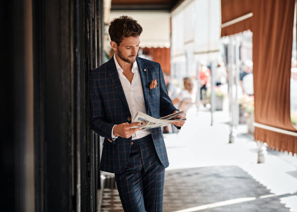 istock Handsome man in suit reading newspaper outdoor 1300966346