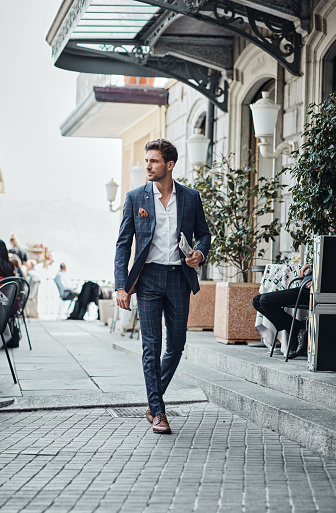 Handsome man in checked suit walking on the street with newspaper