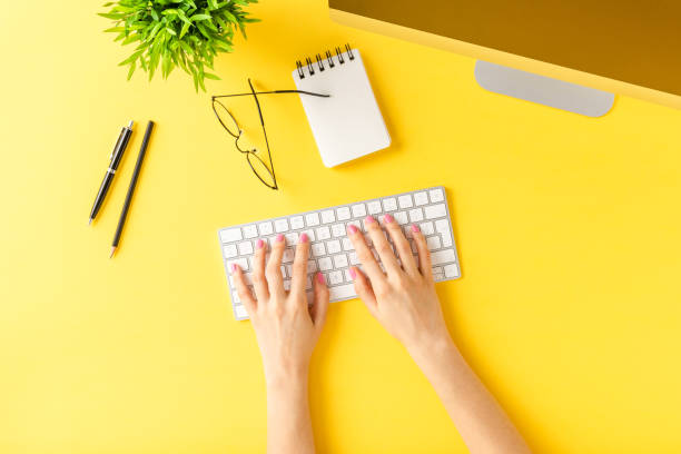 istock Overhead shot of female hands using computer with accessories on yellow table. Office desktop. Flat lay 1300966392