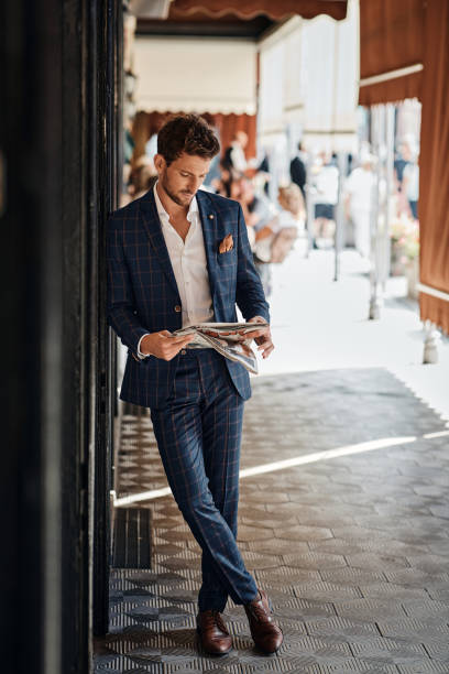 istock Handsome man in suit reading newspaper outdoor 1300966437