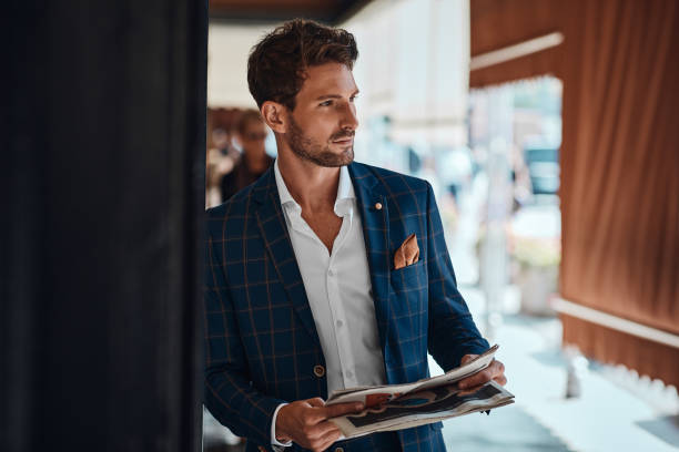 istock Handsome man in suit reading newspaper outdoor 1300966515