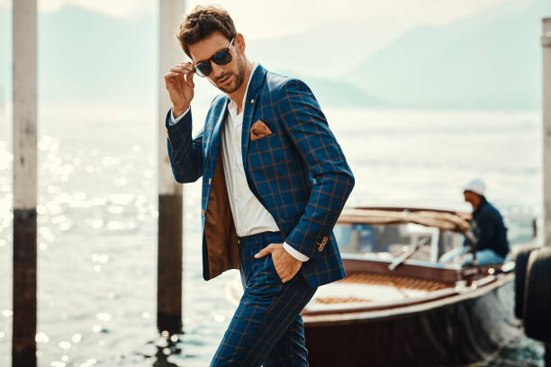 istock Young handsome man in classic suit over the lake background 1300966621