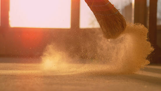 LOW ANGLE: Dust gets swept up into air as person cleans a construction site