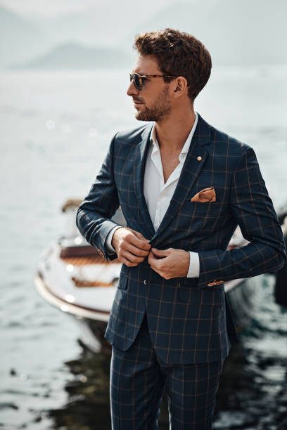 istock Young handsome man in classic suit over the lake background 1300966681