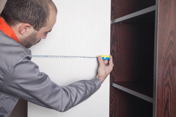 istock Man using tape measure while installing new furniture in home. 1300966865