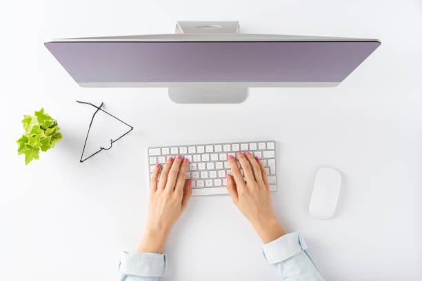 istock Overhead shot of woman’s hands working on computer with business accessories on white background. Office desktop. Flat lay 1300967754