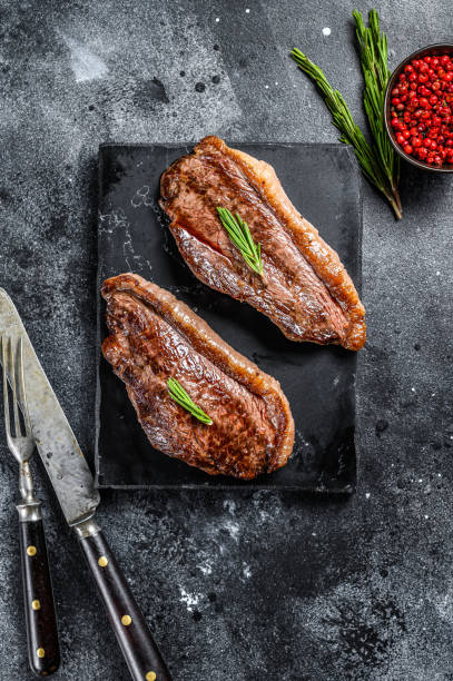 Grilled top sirloin cap or picanha steak on a stone chopping Board. Black background. Top view Grilled top sirloin cap or picanha steak on a stone chopping Board. Black background. Top view. cropped pants photos stock pictures, royalty-free photos & images