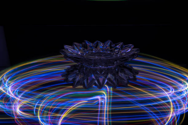 Light painting with small lights on a mirror. On the mirror are elements such as ice, glass ball, light bulb and drinking glass