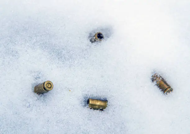 Photo of Four used nine-millimeter pistol sleeves lying in the snow