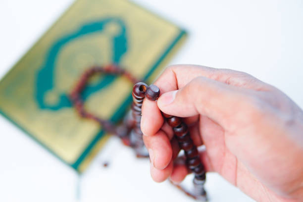 man hand holding a muslim rosery beads, tasbih with quran aside, - praying human hand worshipper wood imagens e fotografias de stock
