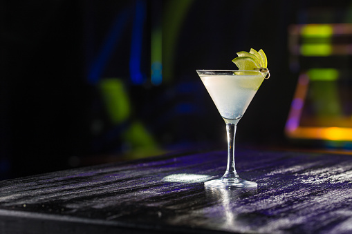 Margarita cocktail with lime slice on bar table on night club background side view