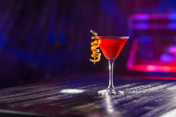 Red cosmopolitan cocktail with orange peel on the table on nightclub background stock photo