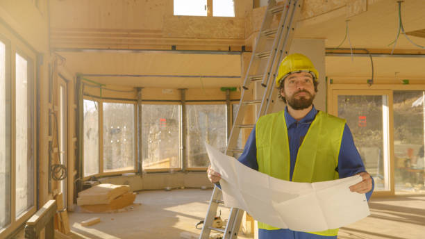 istock CLOSE UP: Project supervisor looks at the plans and a house under construction. 1300969993