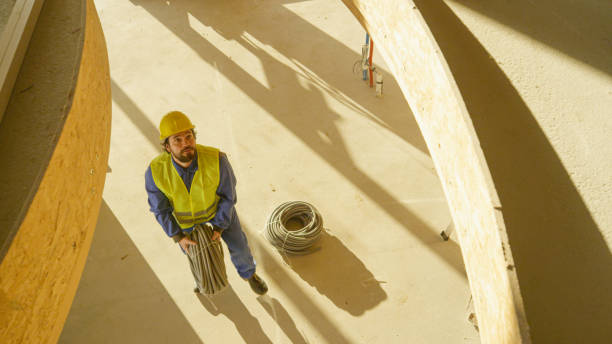 istock Bearded worker throwing rolls of plastic electrical conduits a story higher 1300970009