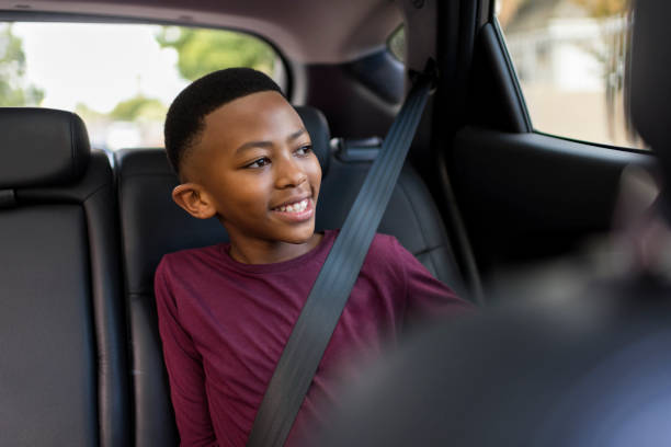 안전벨트를 착용한 어린 소년이 자동차 창 밖으로 바라보고 있습니다. - back seat 뉴스 사진 이미지